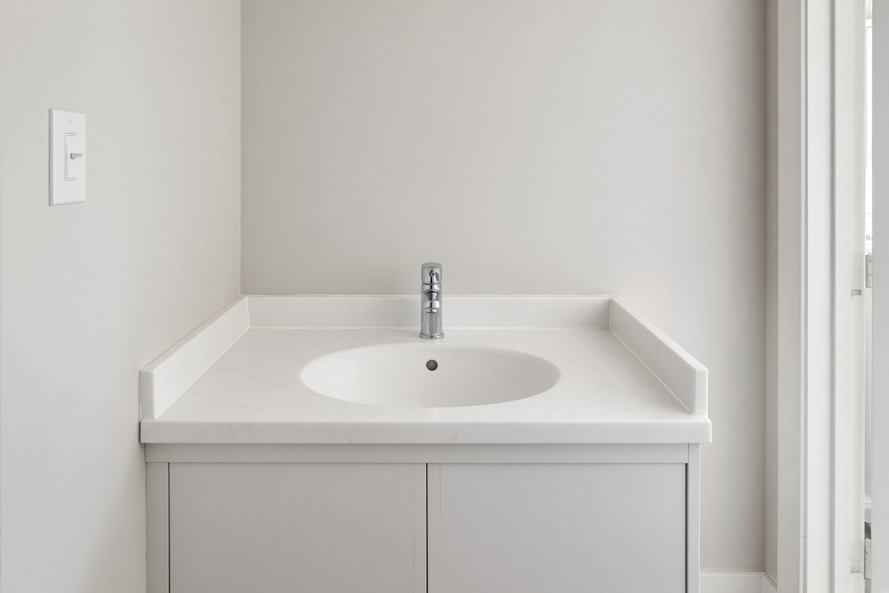 A bathroom vanity with an integrated sink, set in a tight opening between the walls.